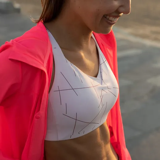 A woman walks in a bright red jacket and Brooks Drive pocket bra