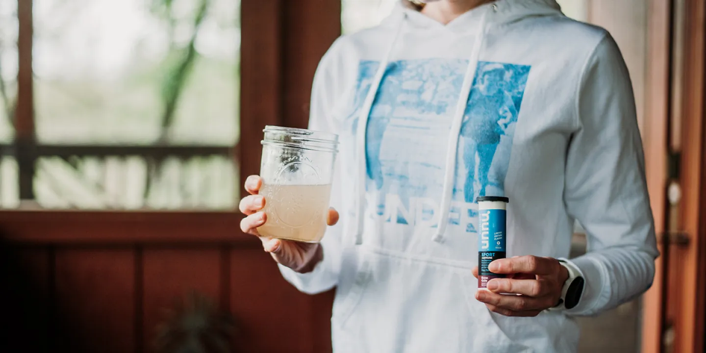 A Woman drinking Nuun Sport out of a mason jar glass