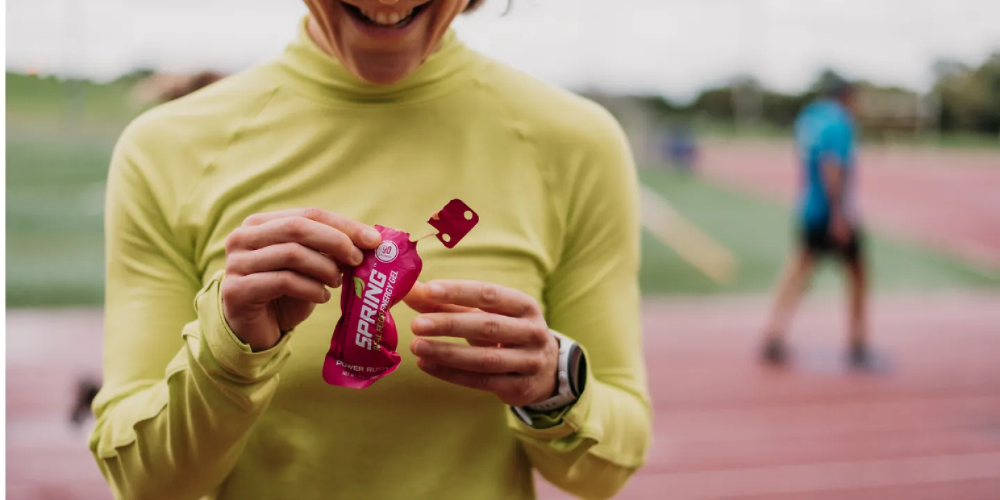A runner opening a Spring Energy gel to eat.