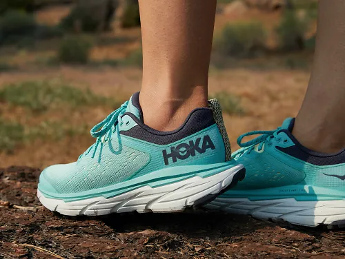 A woman wears the HOKA Challenger ATR 6 in blue