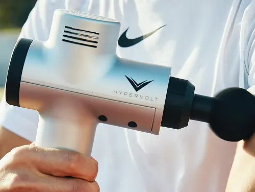 A man uses a Hypervolt percussion massager on his arm