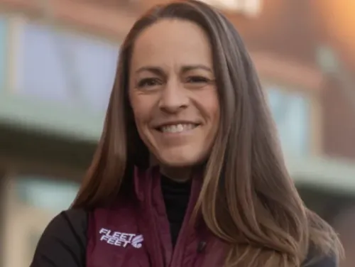 Jenny Simpson stands, smiling, in front of a Fleet Feet store