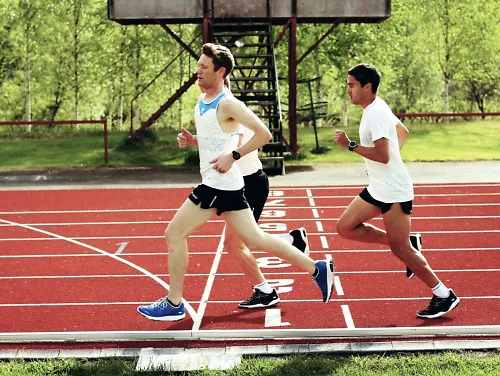 Three Karhu athletes run a workout on a track during a running camp in Finland