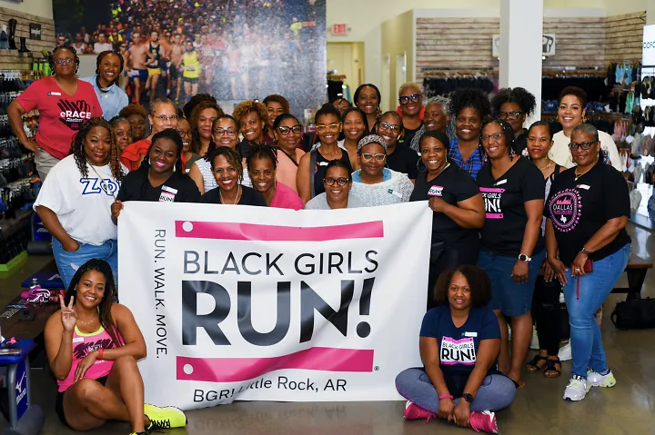Members of Black Girls Run in Little Rock Arkansas smile together with a BGR banner