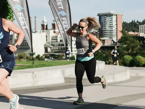 A woman pumps her fist in the air as she crosses the finish line of a race