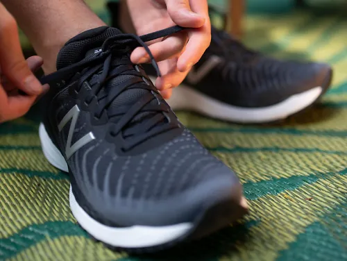 A runner tying a pair of New Balance Fresh Foam 860v11 running shoes
