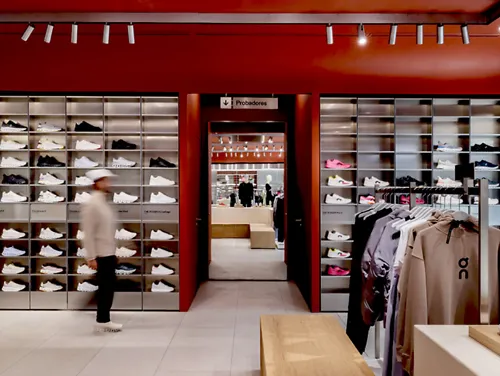 A blurred figure walks through an On retail store