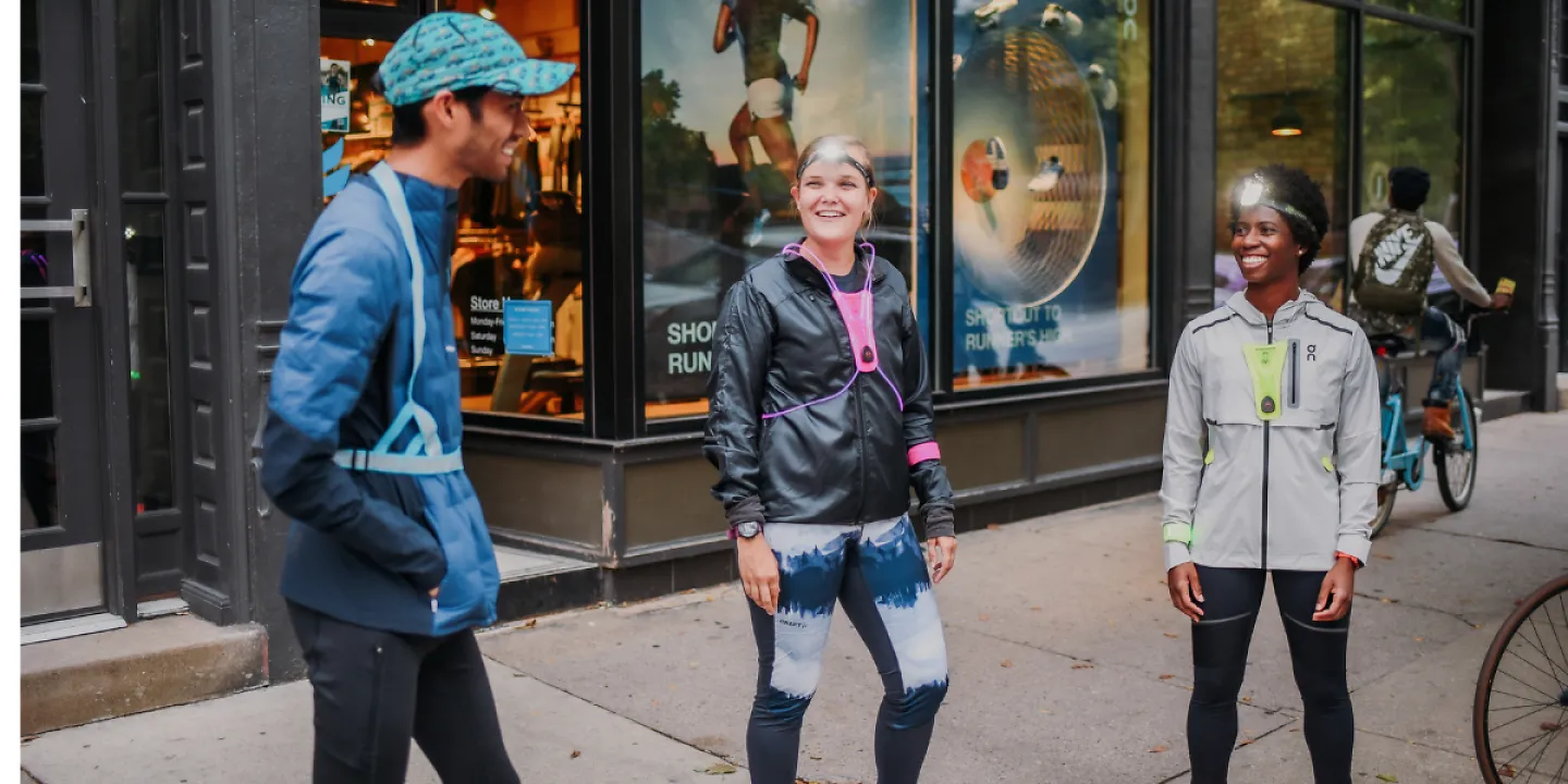 Three runners hanging out with different reflective vests on their bodies.