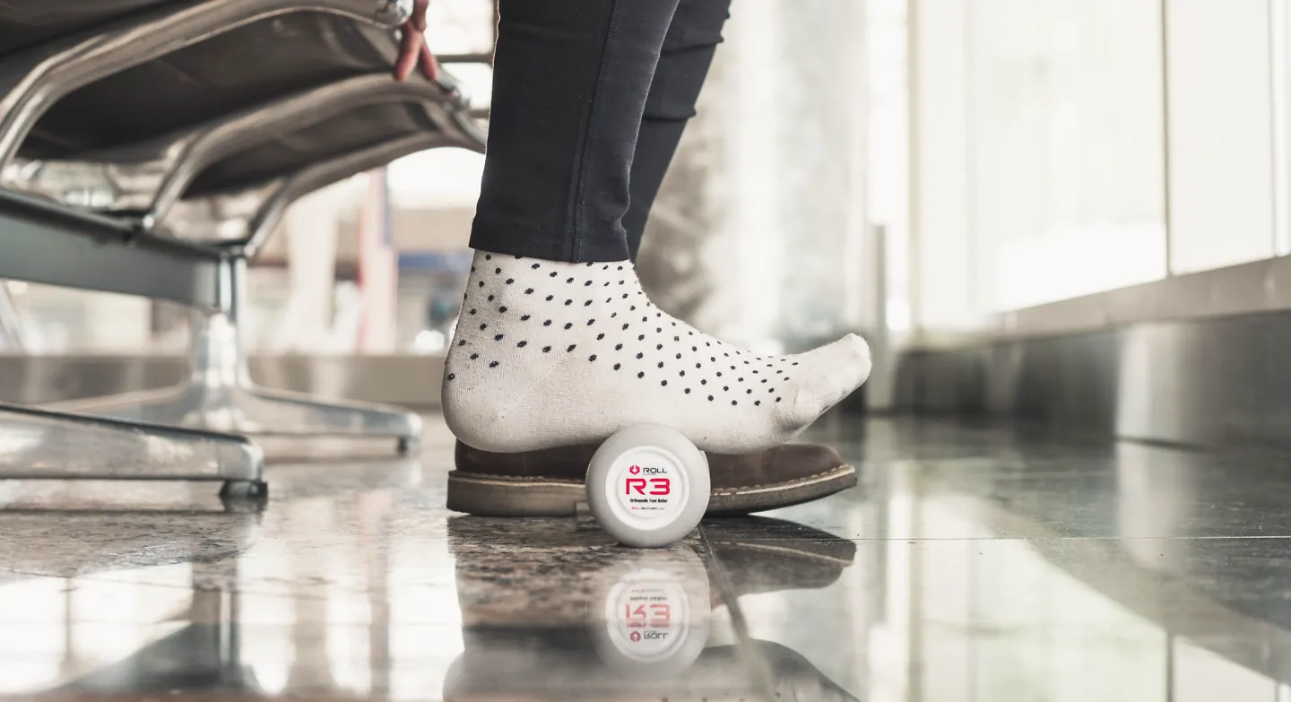 A person using the ROLL Recovery R3 foot massager