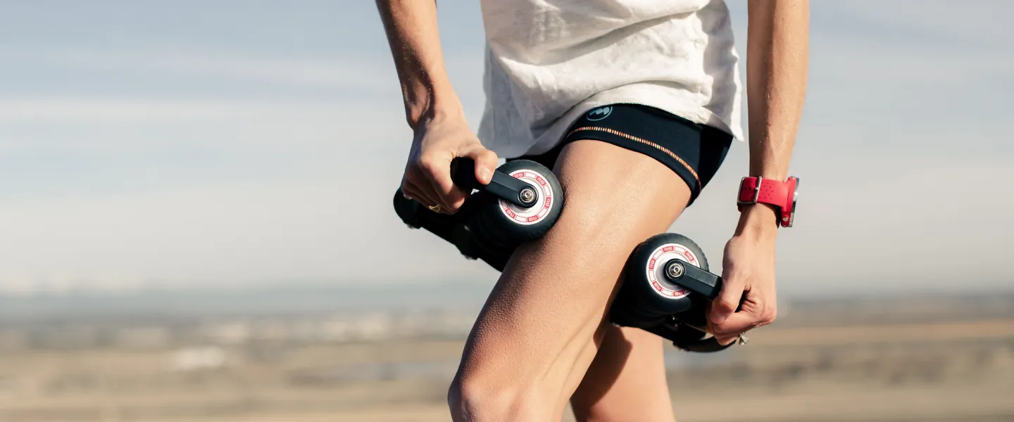 A woman massager her thigh with the Roll Recovery R8