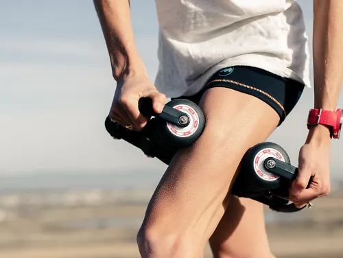 A woman massager her thigh with the Roll Recovery R8