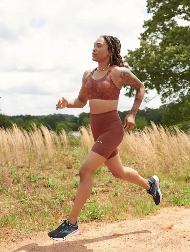 A woman runs in a sports bra and shorts.