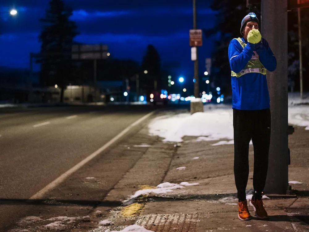 A runner warms his hands during an early morning run in the winter