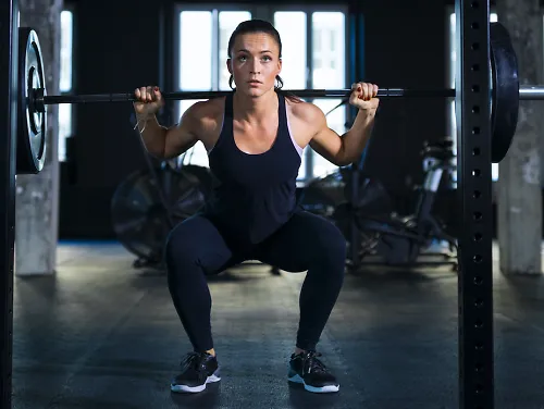 A runner does a squat with a barbell for strength training