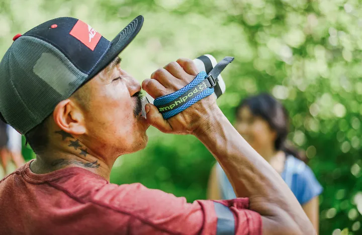 A runner drinks from an Amphipod water bottle during a run