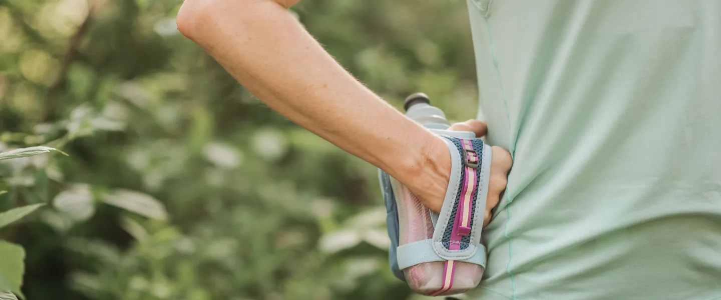 A runner keeps a handheld water bottle to stay hydrated during a summer workout