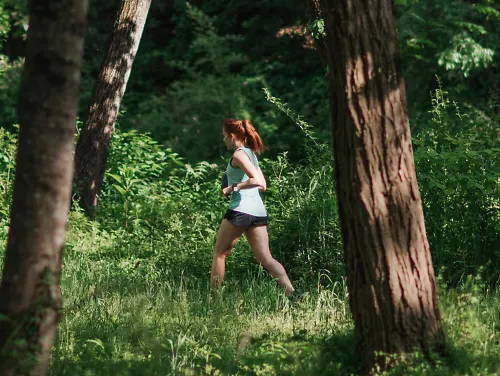 A woman runs on a trail through the woods