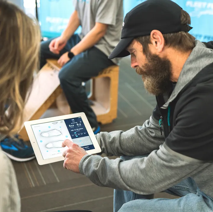 A Fleet Feet outfitter shows a customer a 3D scan of her feet